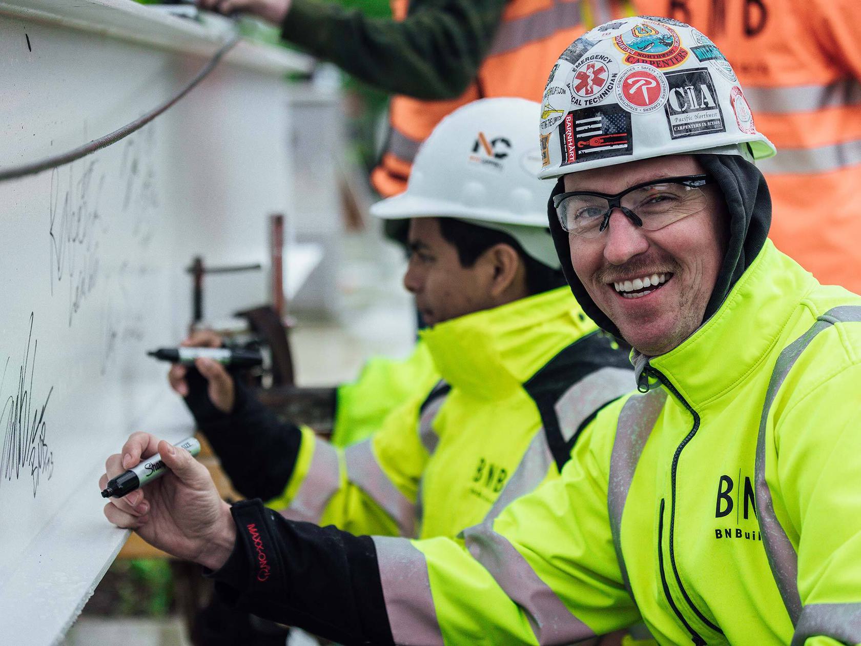 Construction worker in hardhat signing building structure.