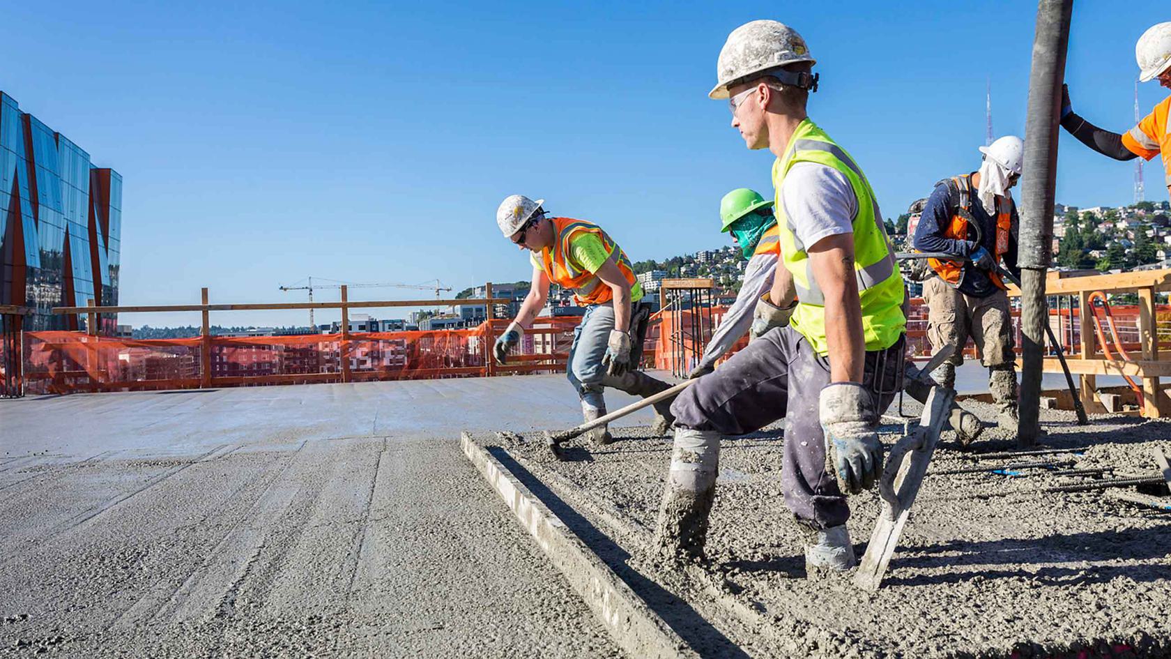 Workers pouring concrete at construction site.