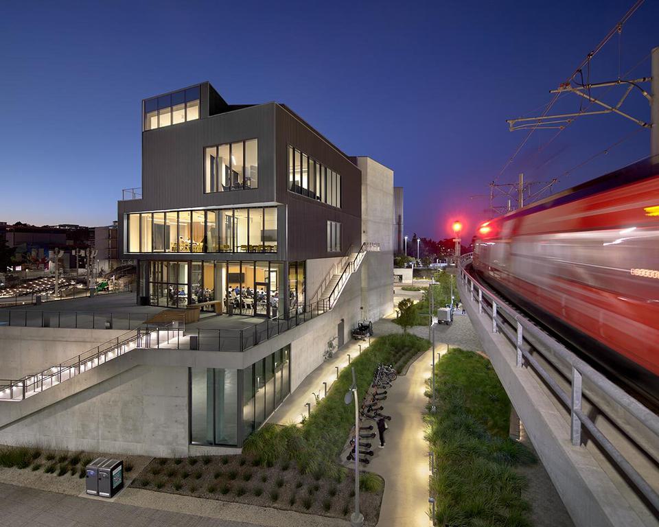 Train passing by a building in the evening.